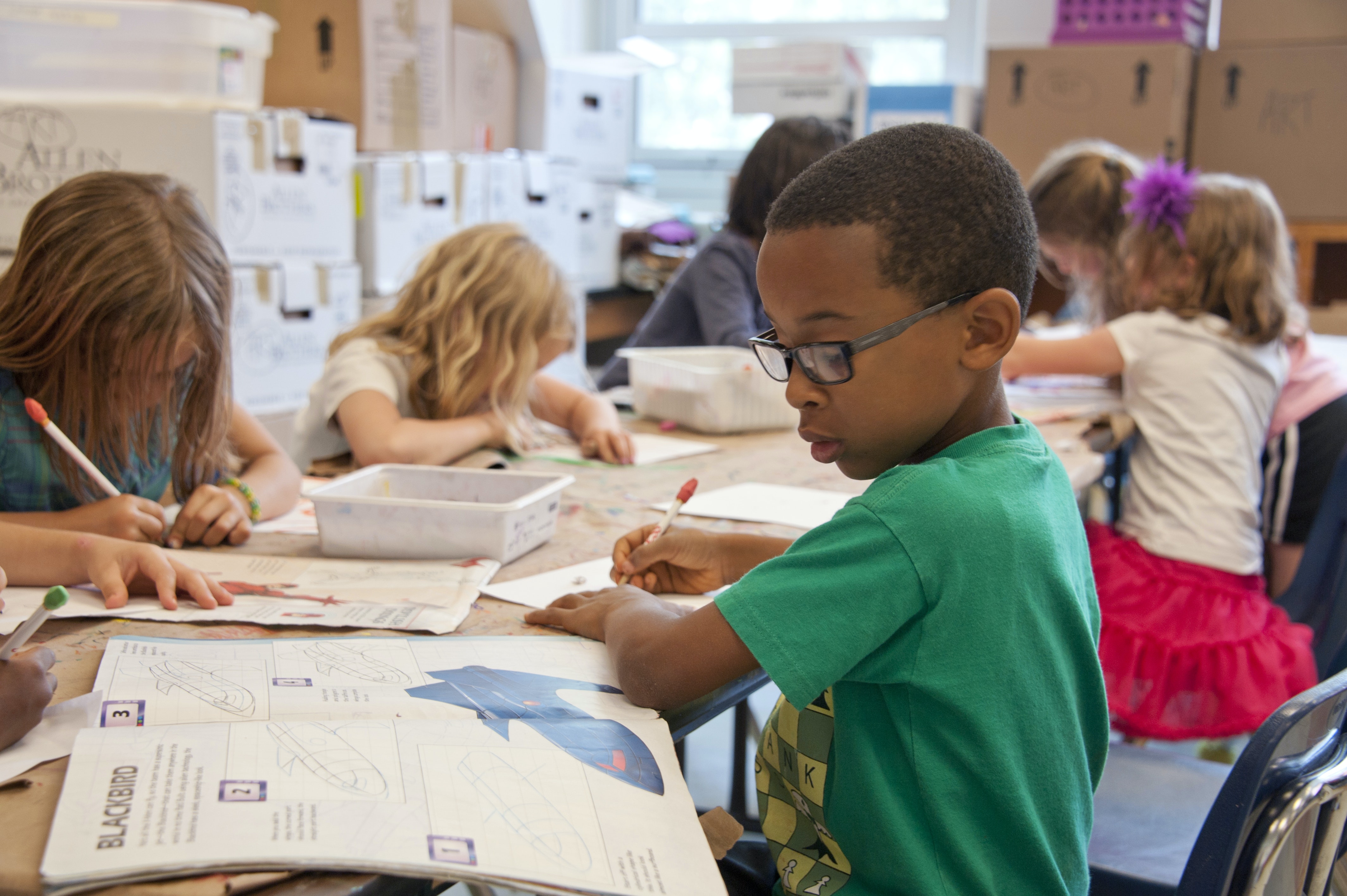 Image is of students sitting at a table writing